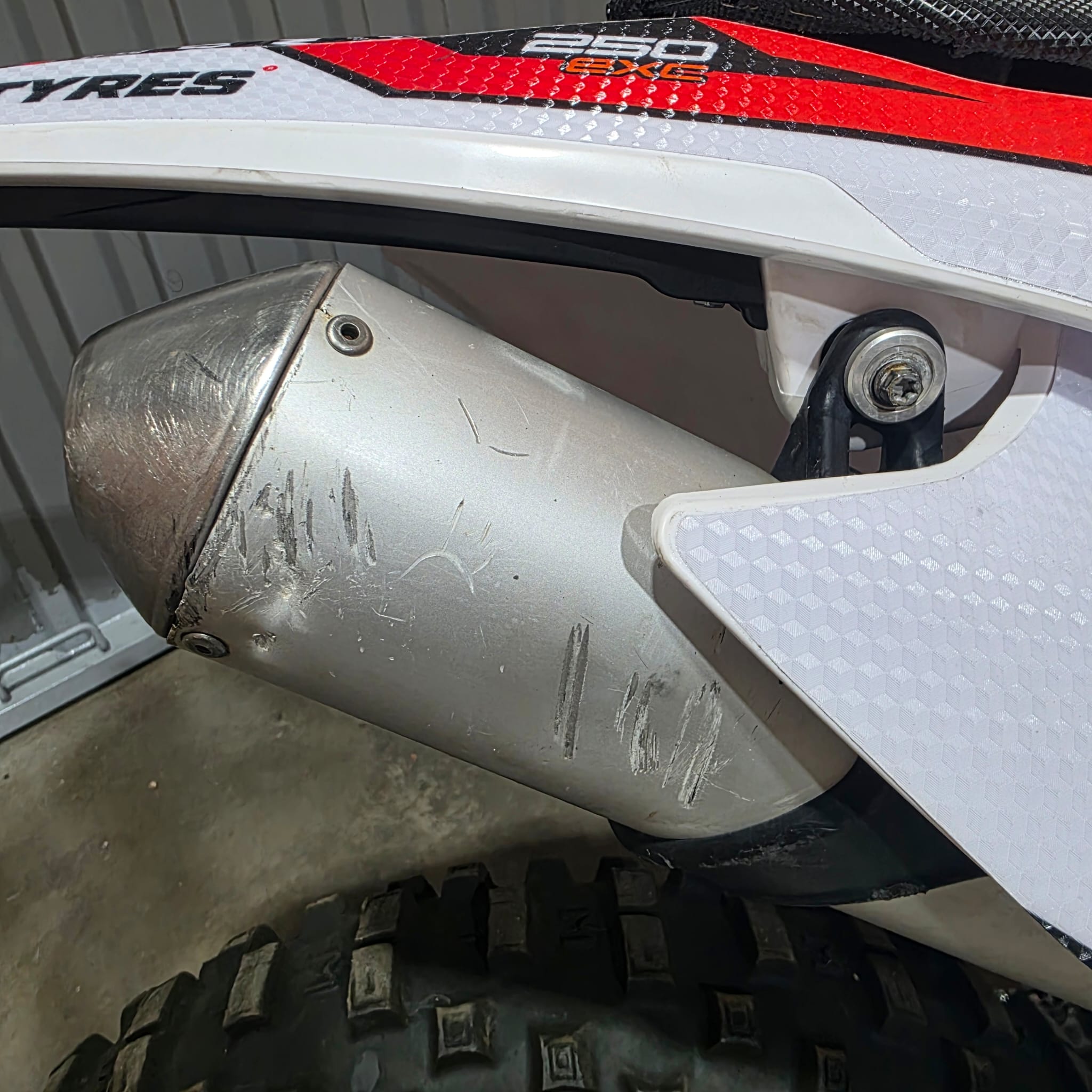 Silencioso de moto de enduro arañado por caídas y golpes