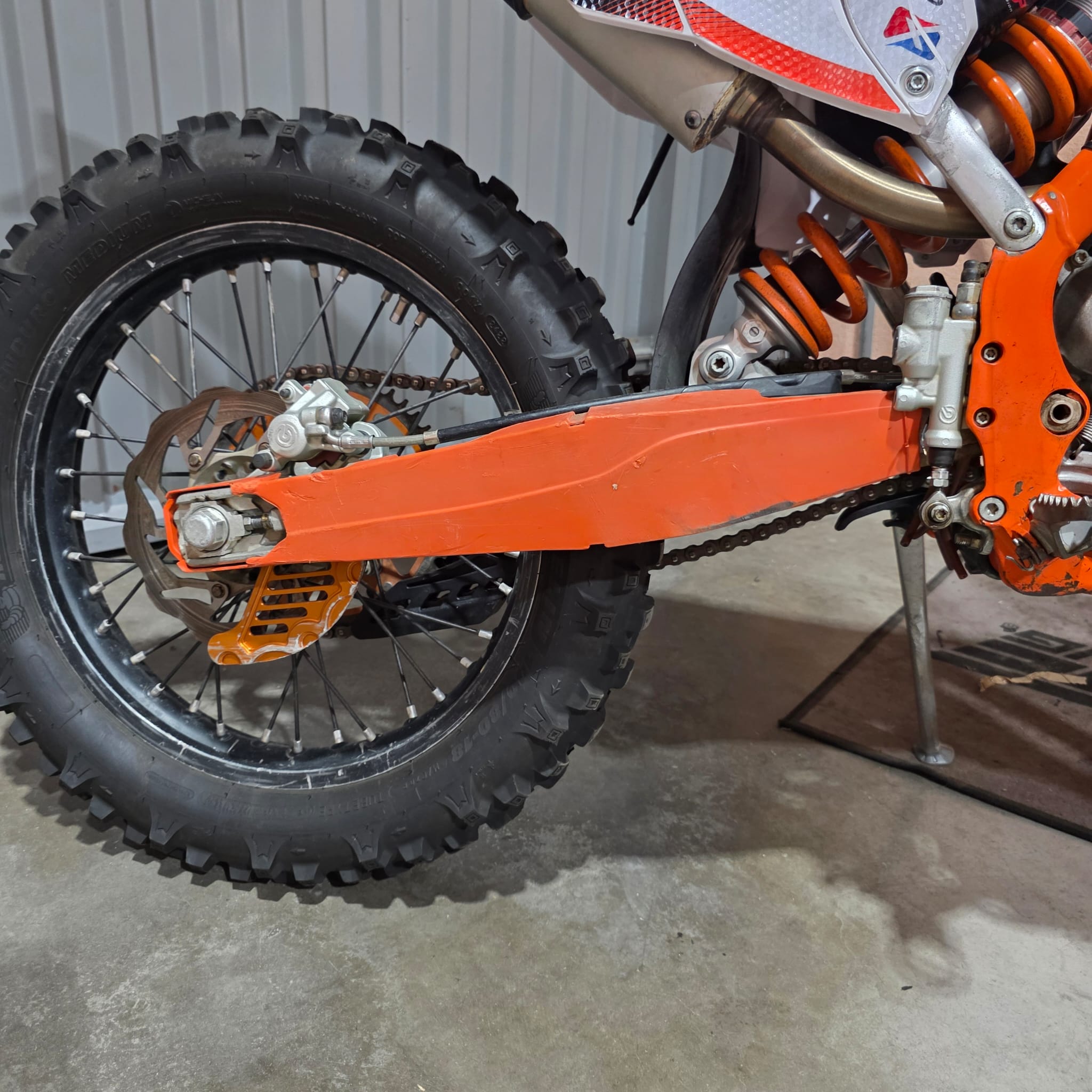 Protector de basculante para moto de enduro con fijación mediante bridas